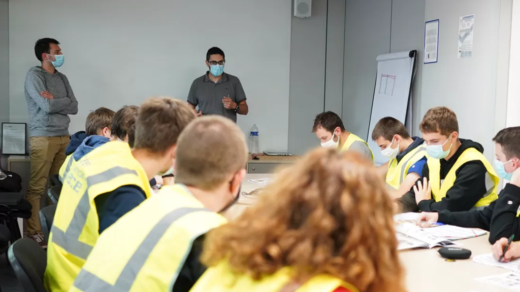 Un groupe d'étudiants à une table écoute notre intervenant en méthodes industrielles